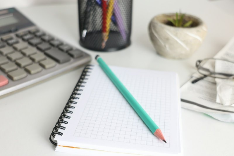 Calculator and notebook illustrating how to write a budget plan for a capstone project