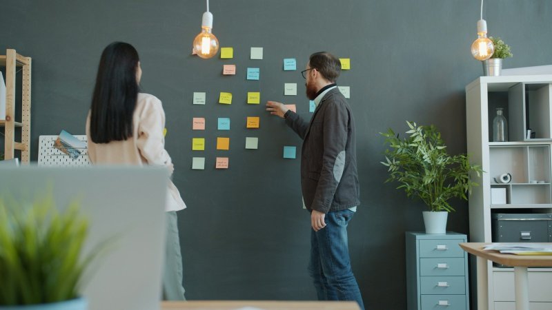 Professionals using sticky notes to plan how to write a scope section for a capstone project